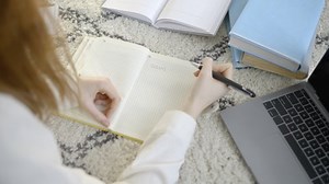 Teenage girl doing homework at home, lying on the floor, distance education