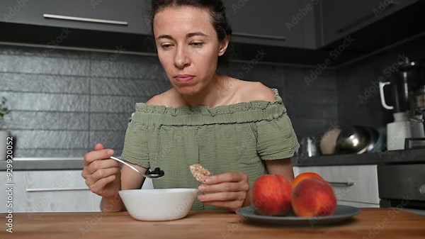 Woman eating fruits and berries at home. Portrait of woman in kitchen enjoy vegetarian dishes, organic healthy food