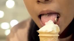 Girl licking Vanilla Ice cream cone with background.