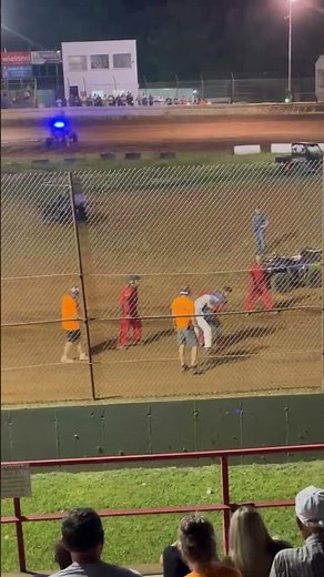 Two drivers fighting on the front stretch of a dirt race track to settle their differences