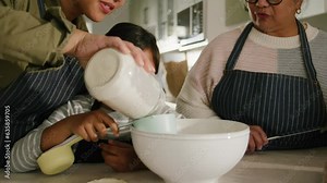 Close up of cute daughter mom and granny baking together in a modern kitchen wearing aprons