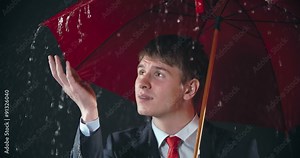 Guy hiding under umbrella in heavy rain and waiting for it to stop
