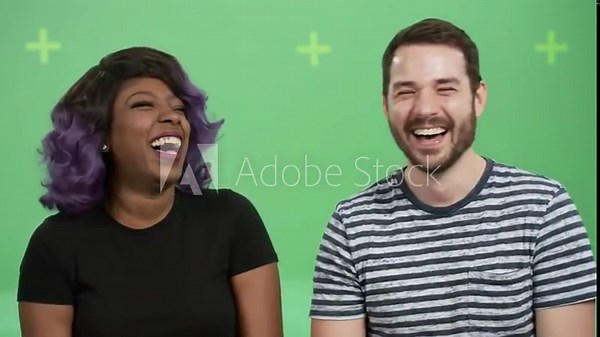 Two people laughing and talking in a studio setting.