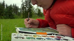 female artist paiting a jungle themed picture with watercolours, outdoors in a nature