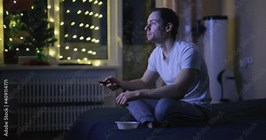 Man watch TV throws nuts and catches them with his mouth during night