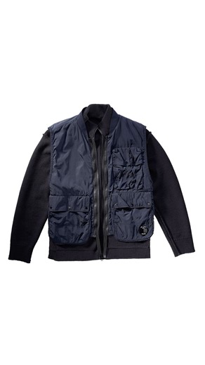 Modular Knitwear | SS026 Knitwear evolves through C.P. Company’s functional design. Two new models shape the range: a reversible cotton jumper with a nylon stretch interior, and a knit featuring a removable Chrome-R vest, introducing a versatile, layered approach. Discover the Spring/Summer 026 collection on cpcompany.com and in flagship stores. | C.P. COMPANY