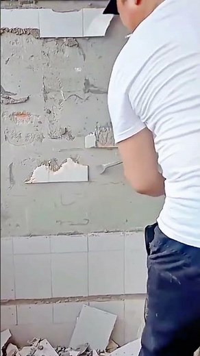 Man carefully removing broken ceramic wall tiles with chisel