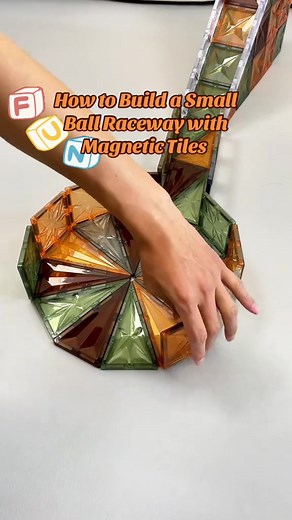 Today we are going to learn how to build a small ball raceway with magnetic tiles. First of all, we are going to build a ramp with square and triangular shaped magnetic tiles, and we are going to use ‘E’ shaped magnetic tiles to make the guardrails of the ramp. Next, we will build the bottom circular chassis with the triangular pieces, and then use the square pieces for the guardrails. This is how you build a ball raceway. The ball can roll up the ramp and into the circular track. This type of p