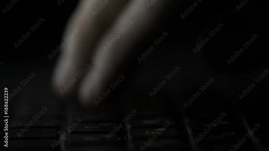 Finger pressing computer keyboard. Male hand is writing text on a laptop macro. Fingers pressing keyboard key on black background