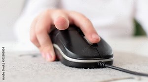 The boy presses the buttons with his fingers and moves the computer mouse to the sides. Close-up of a childs hand spinning the control wheel while playing a video game.