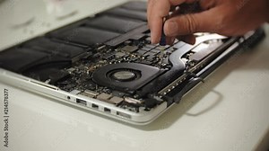 A man is repairing a laptop. The concept of computer repair. Close up of man repair laptop motherboard with a screwdriver. Maintenance of the hardware of the motherboard. Disc holder, computer repair
