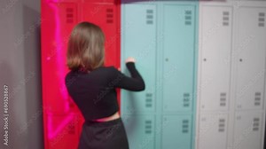 The girls return to the locker room after group exercise. The girl opens the locker in the locker room with a key with a tag