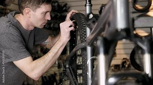Bicycle repair. young mechanic repairs bicycle after trip. man fixes flat tire and checks air leak. Repair service for sports and mountain bikes. Repair of broken frame
