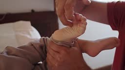 A father tickles his son's foot and smiles. This tender moment...