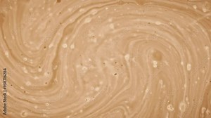 Abstract light brown liquid background. Chaotic flow of viscous, thick creamy water with bubbles. Liquid flow in circles. Coffee with cream texture. Planet like surface