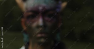 Closeup of a fire Mystical performer in tribal face paint, holding a flaming burning stick. Capturing intense emotions and ancient rituals in a dark outdoor scene with a mysterious vibe.