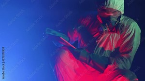 Close-up of scientist examining chemical condition at a power plant using a digital tablet to write down notes. young man in protective wear working at atomic station at night.