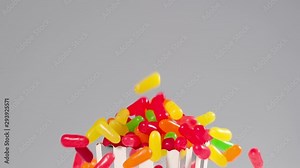 Colorful candy falls in slow motion and bounces on a white surface