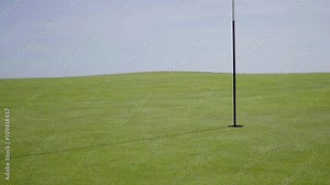 Flag in middle of golf course with slightly worn out green turf grass surrounding hole