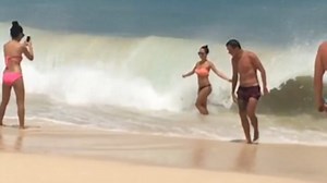 Unsuspecting beauty wiped out by wave posing for perfect bikini shot