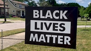 Black Lives Matter sign in the front yard of a suburban city home. BLM sign proudly placed on a quiet street to show support for the community.