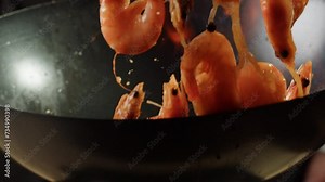 Chef cooking flambe shrimps with oil on wok frying pan close-up. Prawns on fire throwing them in pan. Restaurant Food concept. Sea food.