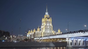 Download Moscow 2021. Action. Beautiful huge evening buildings near the river in Moscow were shot from afar on a dark evening with bright lights and lanterns that glow .