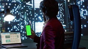 Qualified consultant operates on famous global company while looking at mobile device with greenscreen interface. In skyscraper office building, business leader checks isolated copyspace display.