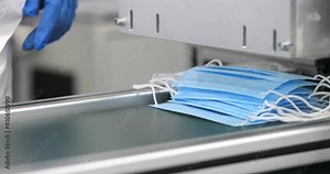 Covid protection. Manufacture of surgery masks. Medical mask on conveyor belt in the workshop of medical clothing factory. Production of disposable medical clothing for protection against the virus.
