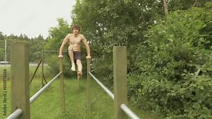 Fit young man performs L-Sit core strength exercise on parallel posts
