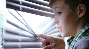 Eager Exploration: Delighted Young Boy Opens Blinds and Explores the World Outside the Window