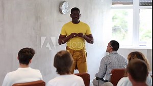 Positive friendly African American male tutor giving lecture to group of men as part of educational program