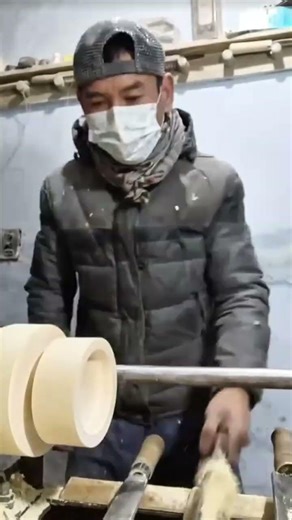 shaping a large wooden block on a lathe with specialized tools to create a smooth circular object