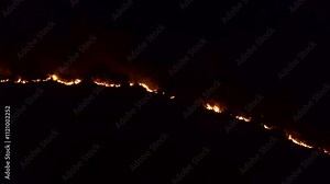 Wildfire raging along mountainside at night through fire prone fynbos vegetation