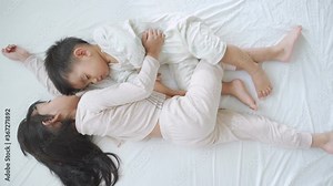 Asian sibling of sister and brother are sleeping together on the white bed in the morning time and the wake up for resting time.