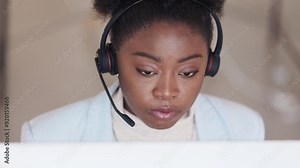 Call center or customer support agent taking a call from a client using headphones while sitting inside. Friendly remote worker answering a customer to offer a service or explain a product query