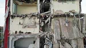 Hard destruction of a building in a residential area, destruction of rubble with the help of industrial equipment, view of the ruins of an office building.