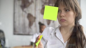 Business woman using sticky notes solving strategy on glass whiteboard