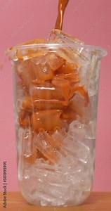 4K footage vertical video Front view SLO MO CU, iced tea being poured into a clear glass full of ice.