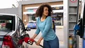 Cheerful woman at a gas station refueling her car - Lifestyles...