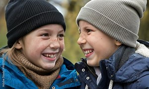 Sibling Connection: A close-up of two siblings of different ages, laughing together, with their faces close, capturing a moment of joy.