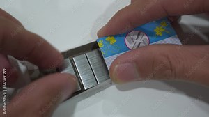 Male hands opening general purpose staple wire inside paper box close up view on white table desk. Stationary and office supply concept