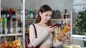 Female purchaser scanning QR code or barcode of peach juice in supermarket . High quality 4k footage