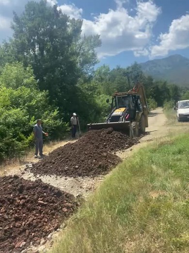 Backhoe Loader Maneuvering Soil in Rural Setting