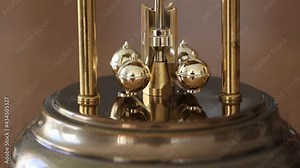 close up of a golden rotating pendulum of a clock indicating time running