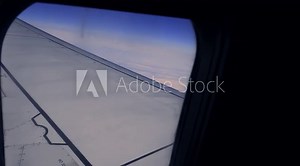 View of window with clouds and airplane wing during the flight at high altitude - view through the plane window