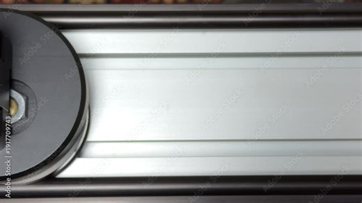 The motorized camera slider moves along its metal rails with steady precision. This automated motion generates a smooth, quiet engine hum and a soft mechanical whir from the drive belt.