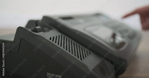 Man's hand picks up the phone and dials 911 rescue service on an old push-button telephone. Side view, close-up. Red blue light flashing on the background