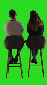 Vertical Video Rear View Studio Shot Of Man And Woman Sitting On Stools Facing Away From Camera Against Green Screen 1 | Free Stock Video Footage