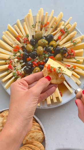Marinated Cheese & Olives - a unique, festive and delicious appetizer and a fun change from cheese boards! INGREDIENTS 2 (8-ounce) package Roth Grand Cru, thinly sliced 2 (8-ounce) package Roth Havarti, thinly sliced ¼ cup olive oil ¼ cup red wine vinegar 4 garlic cloves, minced 2 Tbsp chopped parsley 2 Tbsp chopped mint ½ cup green olives ½ cup black olives 2 Tbsp minced red peppers INSTRUCTIONS 1. Thinly slice the two types of cheese and place them on a circular plate alternating between the t